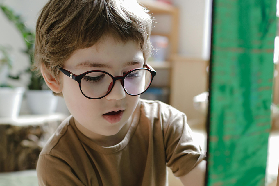 child with glasses painting